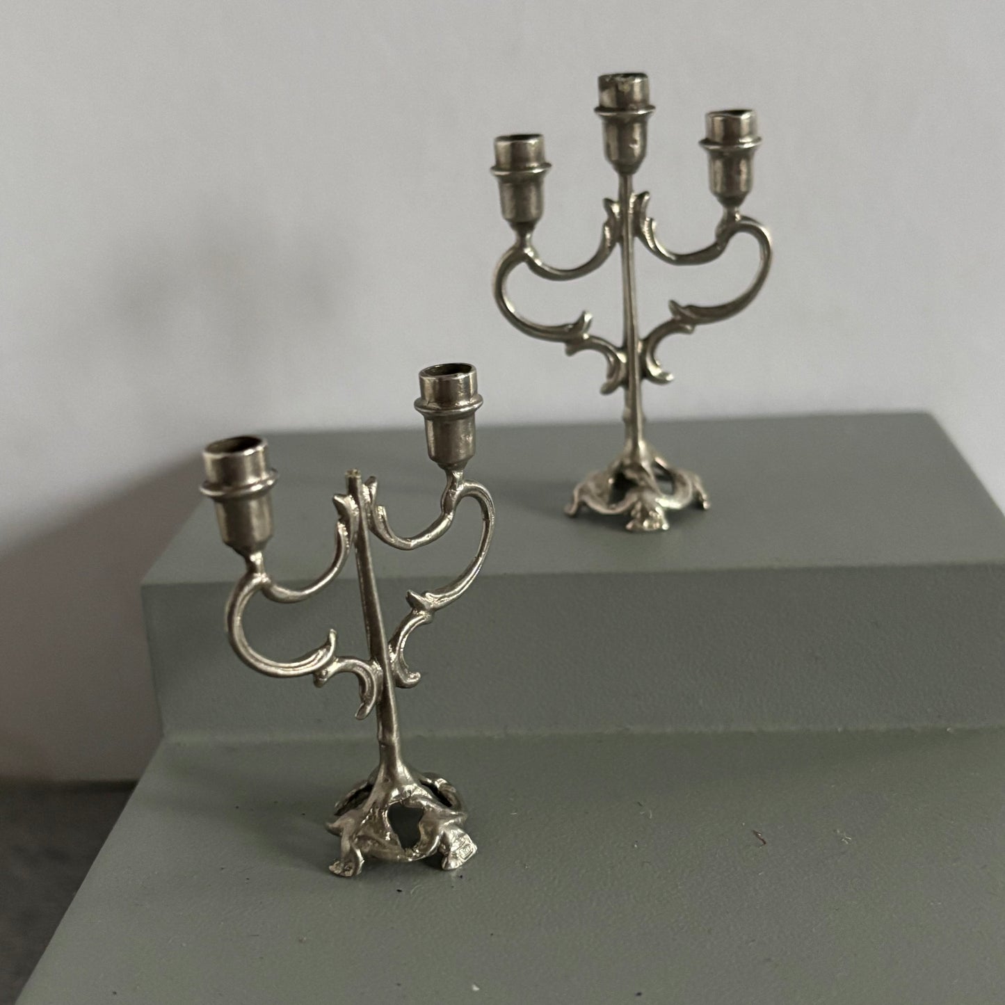 Two silver candelabras on a gray surface with a neutral background