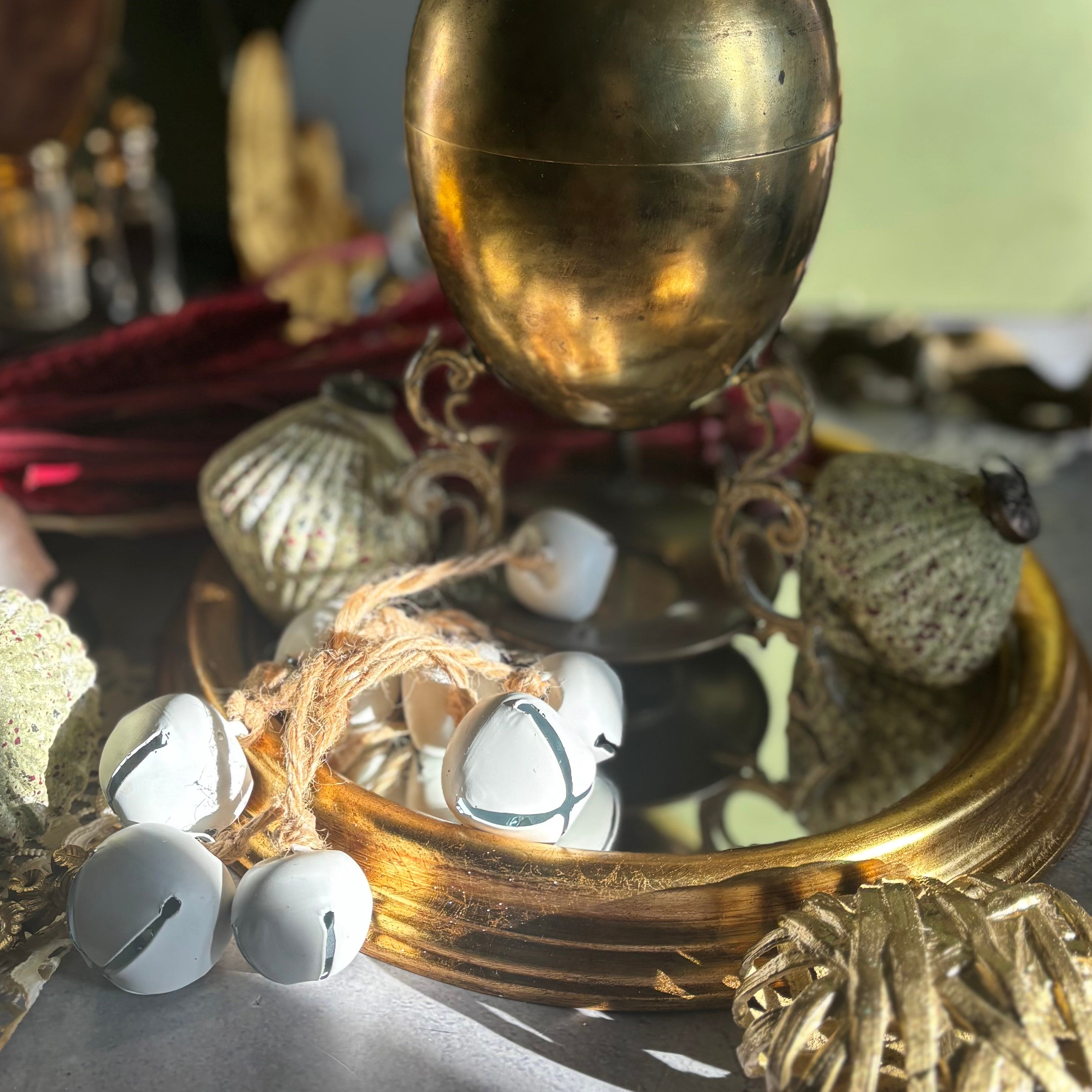 Decorative items including a gold sphere, white stones, and natural elements on a reflective surface.