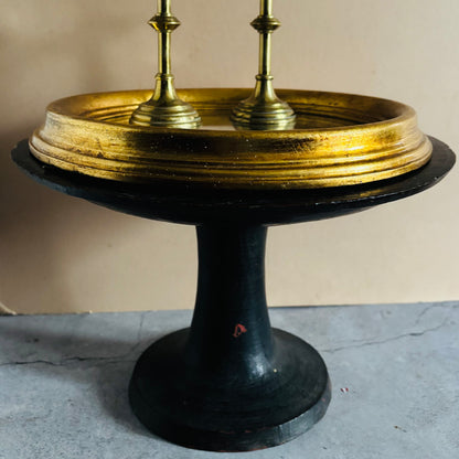 Decorative object with gold top and black base on a gray surface.