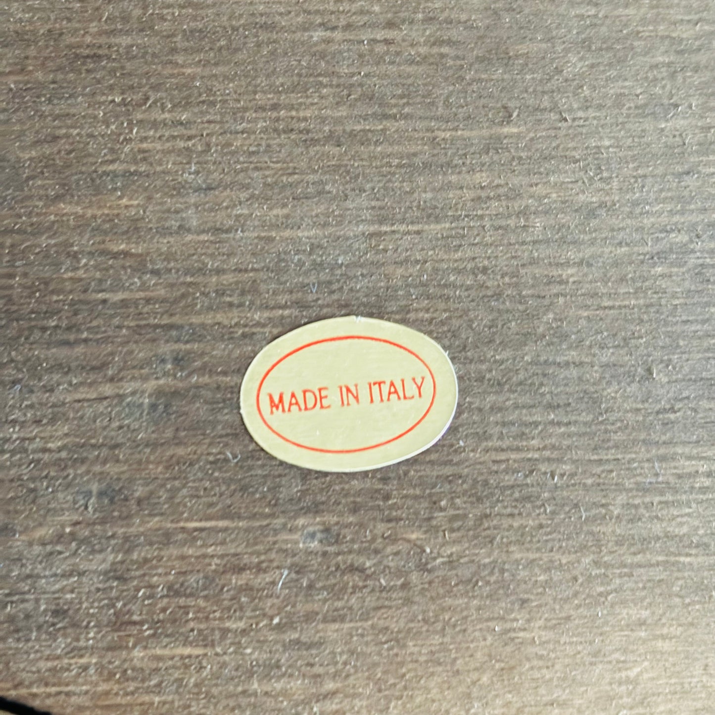 Small oval 'MADE IN ITALY' sticker on a wooden surface