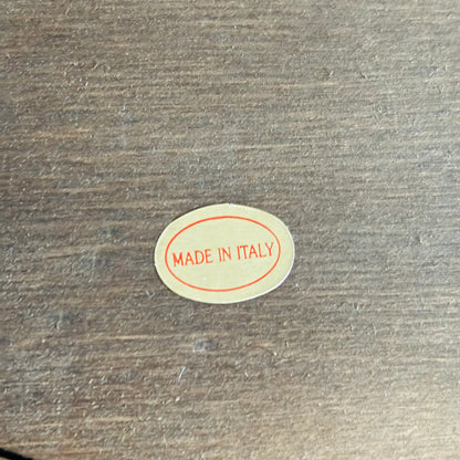Small oval 'MADE IN ITALY' sticker on a wooden surface