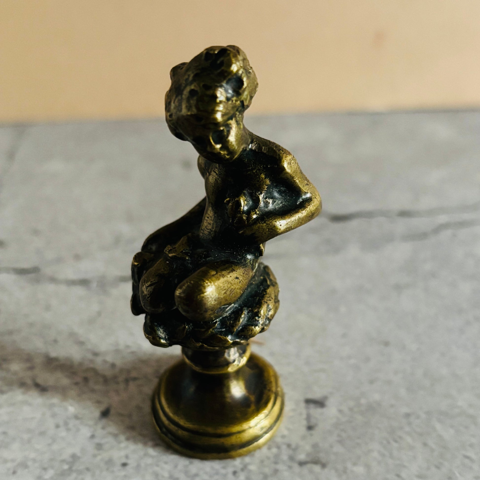 Bronze statue of a seated figure on a marble surface