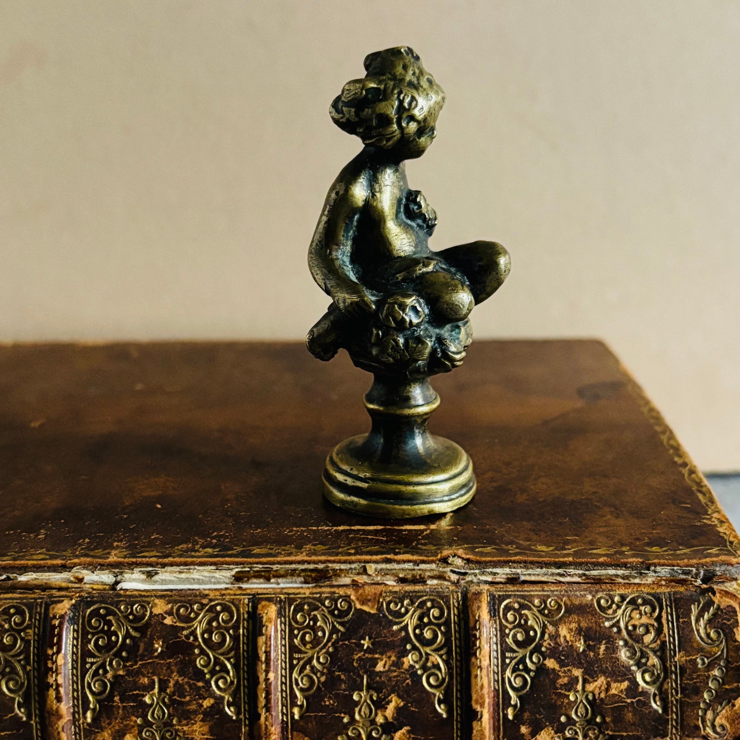 Bronze sculpture of a nude figure on an ornate antique leather book