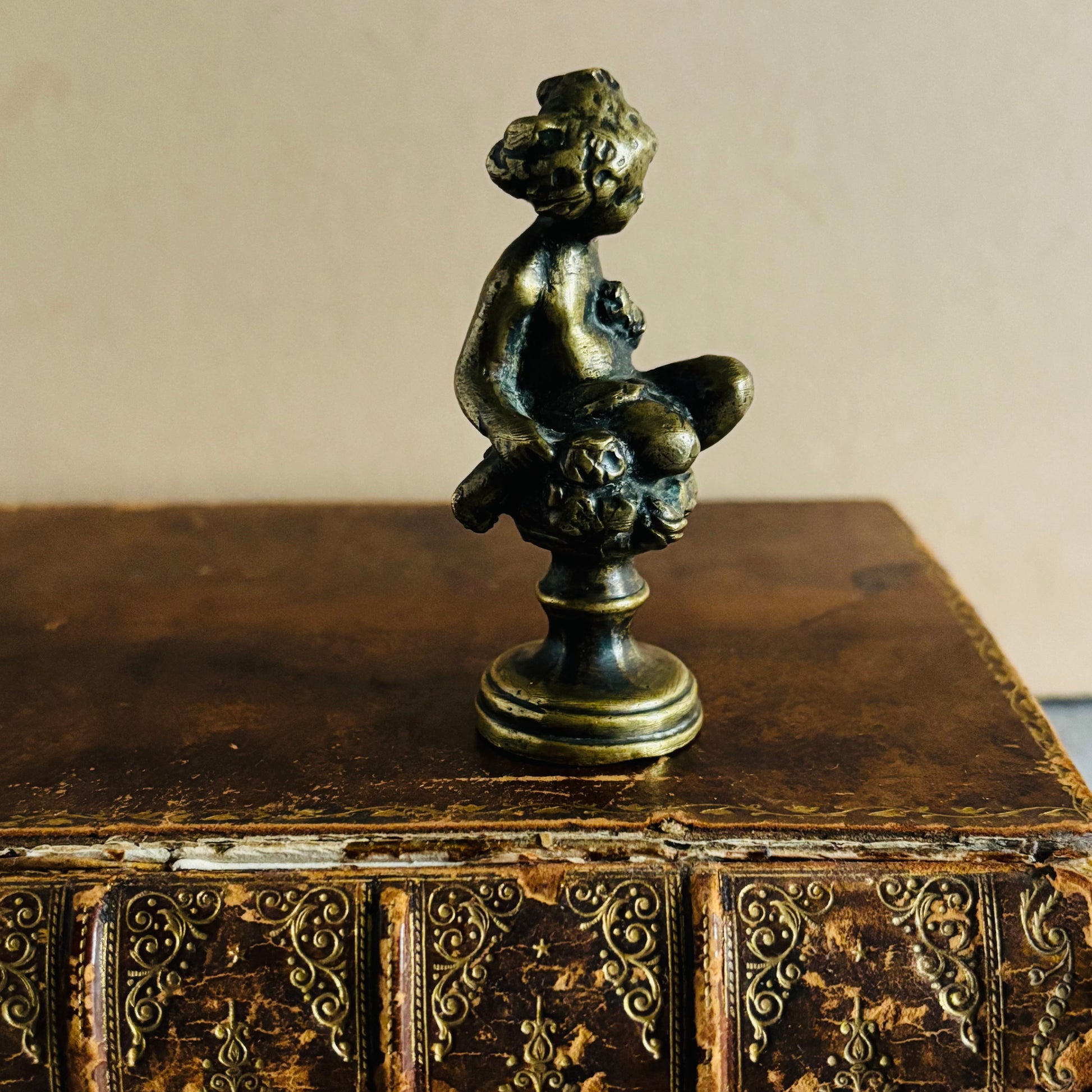 Bronze sculpture of a nude figure on an ornate antique leather book