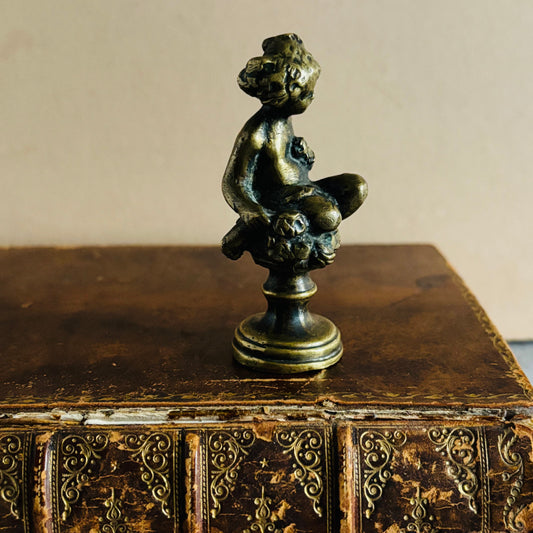 Bronze sculpture of a nude figure on an ornate antique leather book
