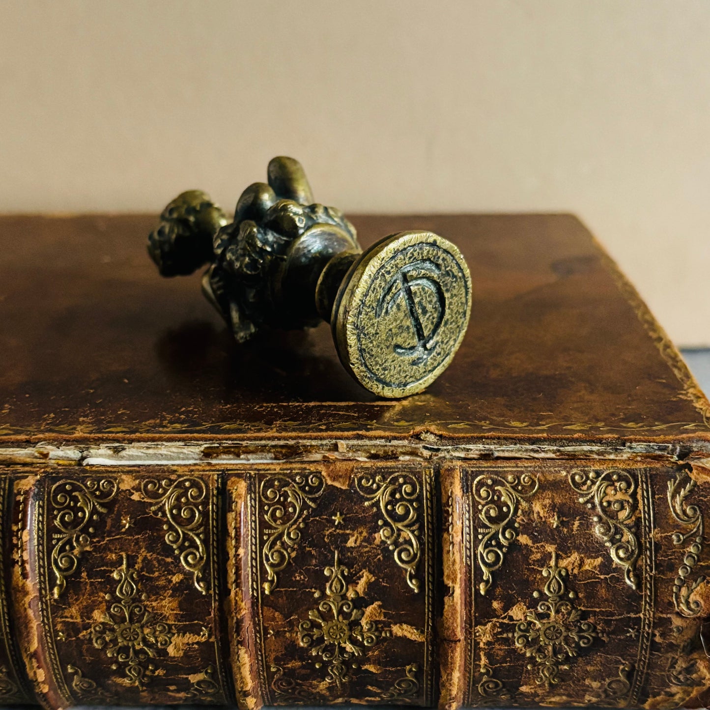 Bronze seal on an ornate leather book with a plain background