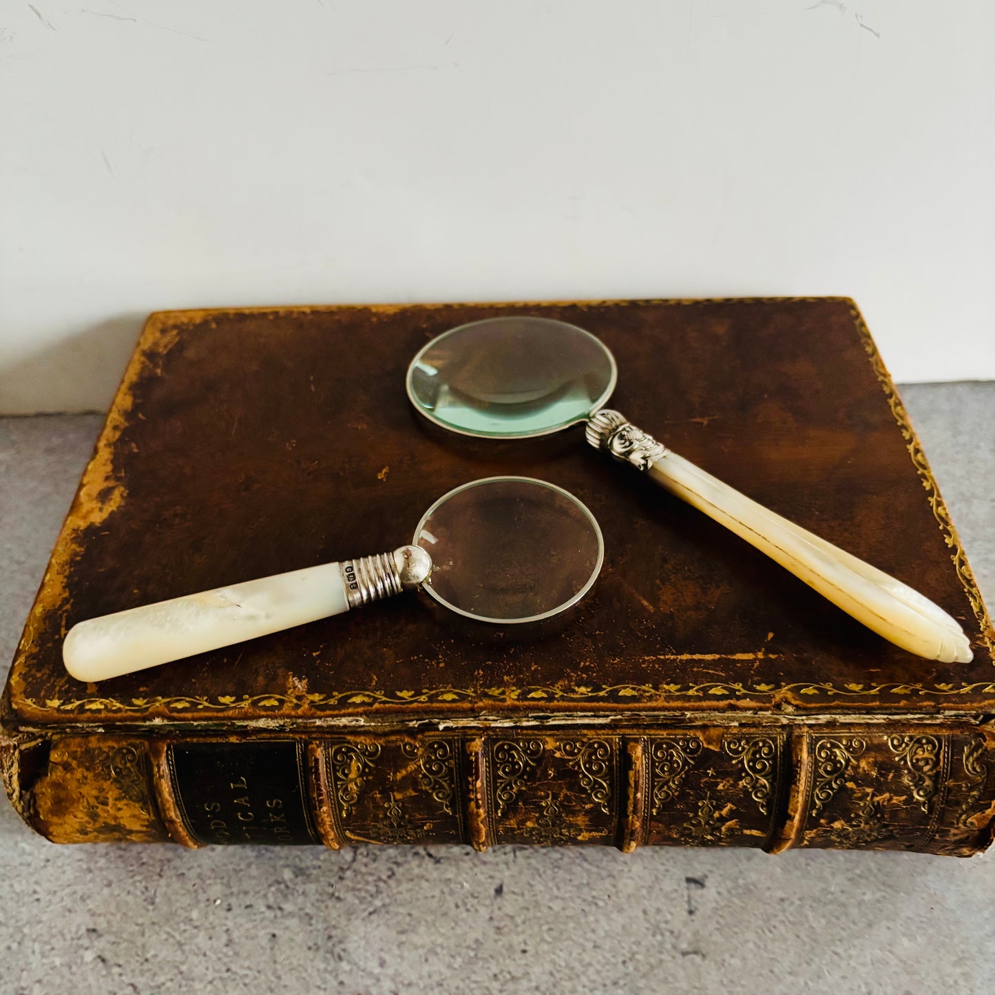 Two vintage magnifying glasses on an old book with a white background