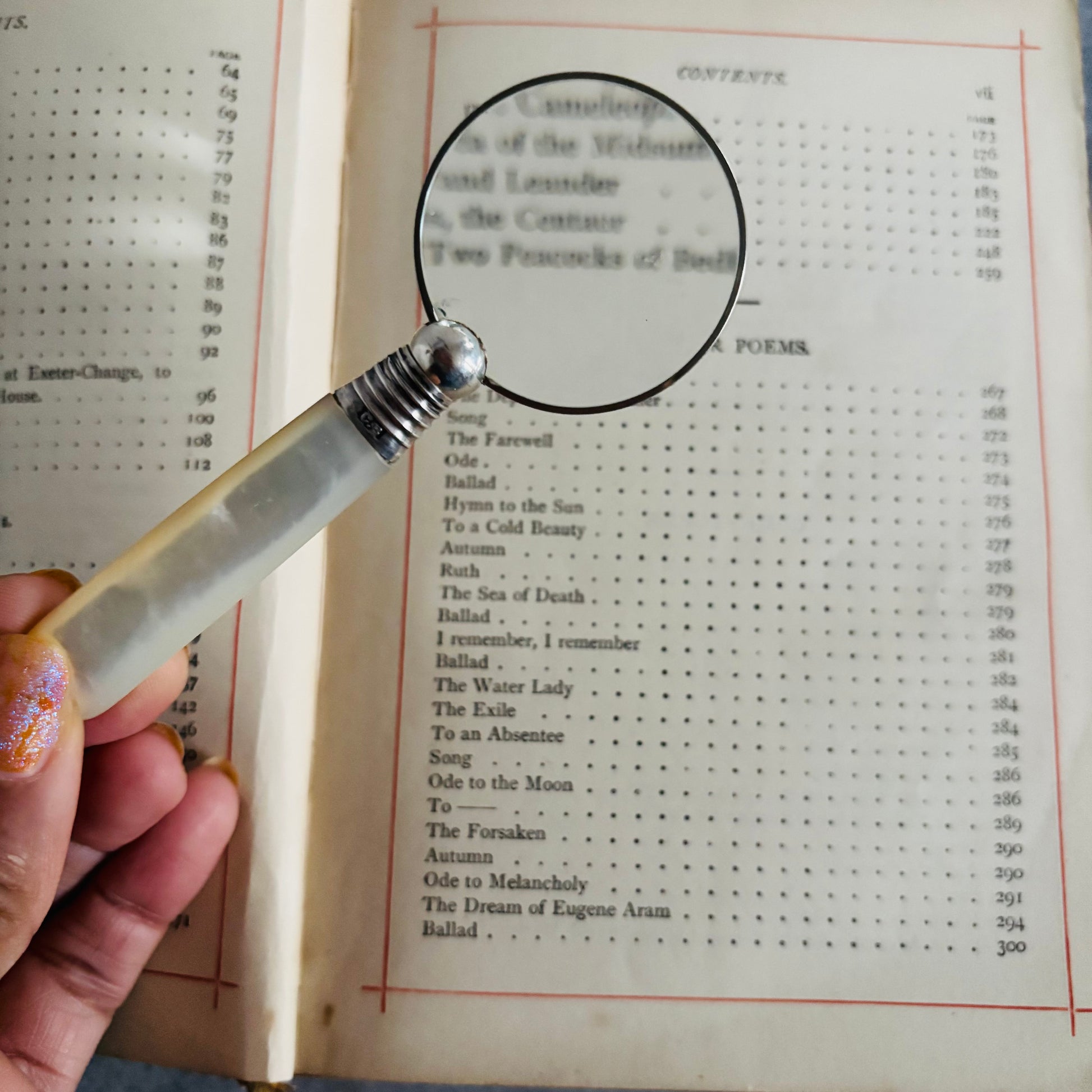 Hand holding a magnifying glass over an open book with text