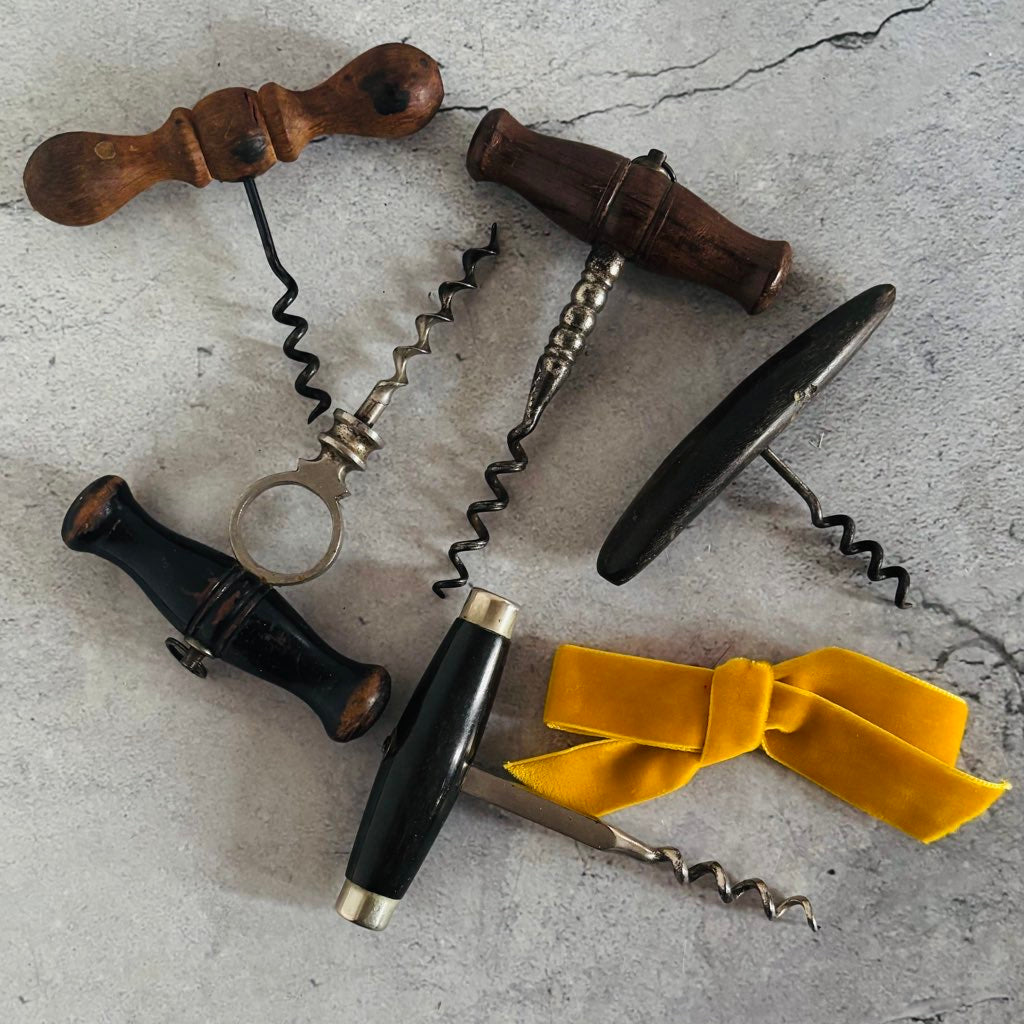 Collection of vintage corkscrews on a textured surface with a yellow ribbon.