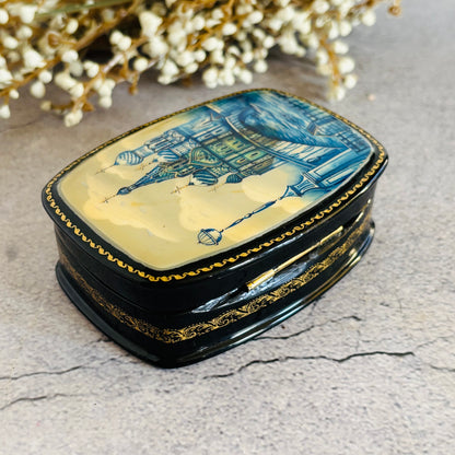 Decorative jewelry box with artistic design on a textured surface with flowers in the background