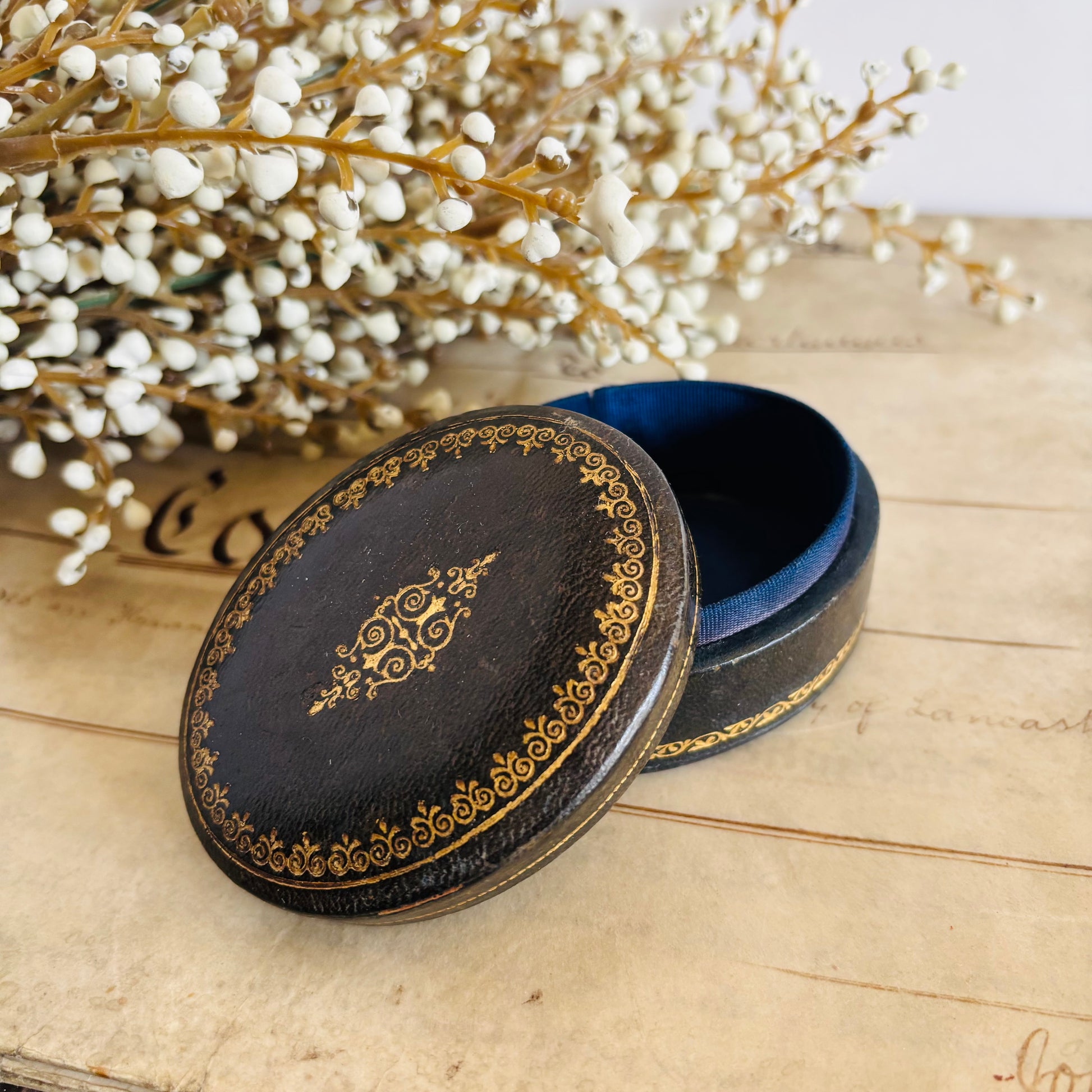 Decorative black box with gold patterns on a with white flowers in the background