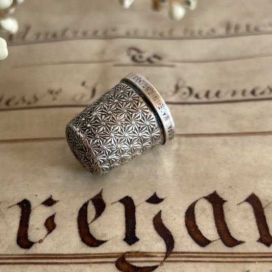 Silver thimble with geometric pattern on an old document