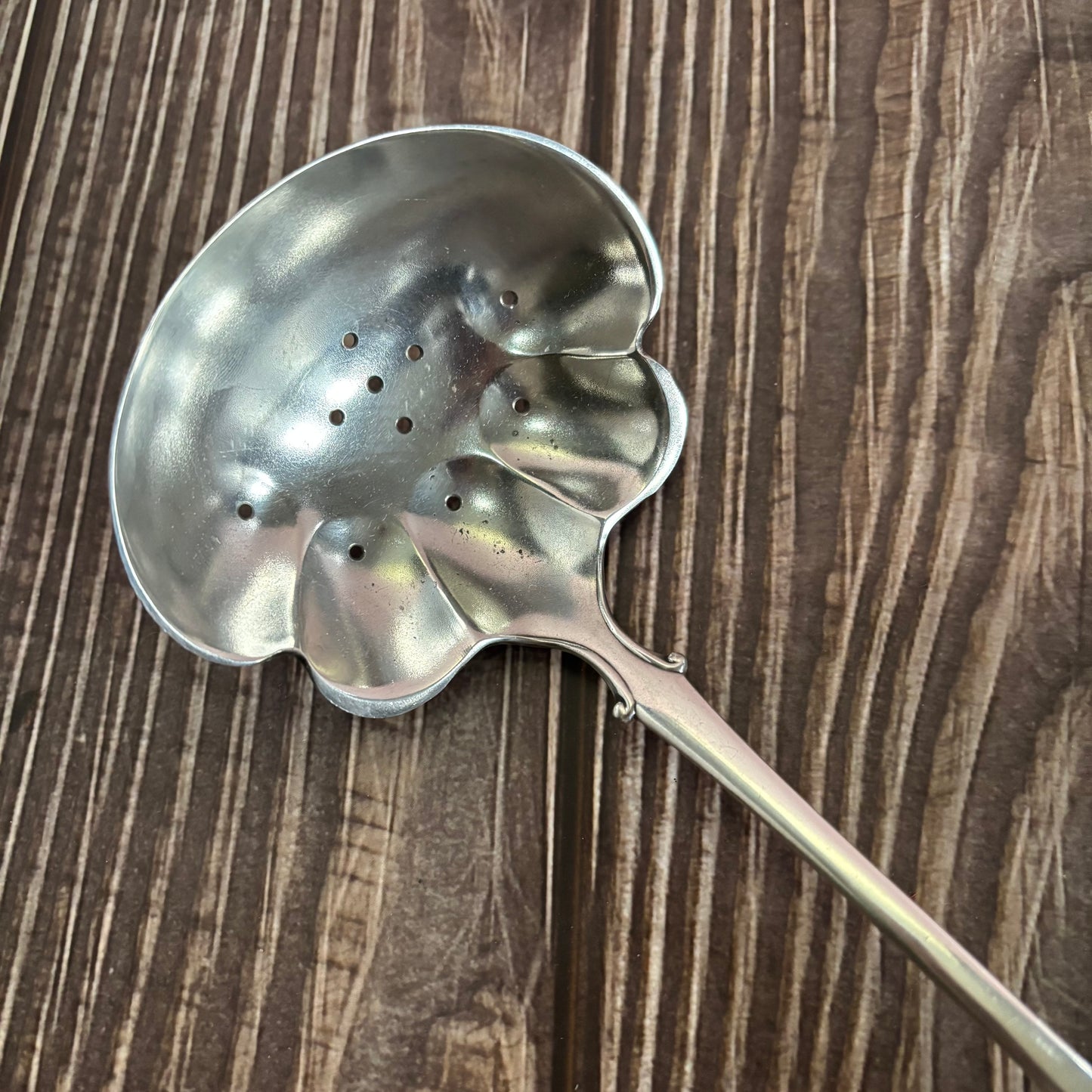Metallic ladle with a unique design on a wooden surface
