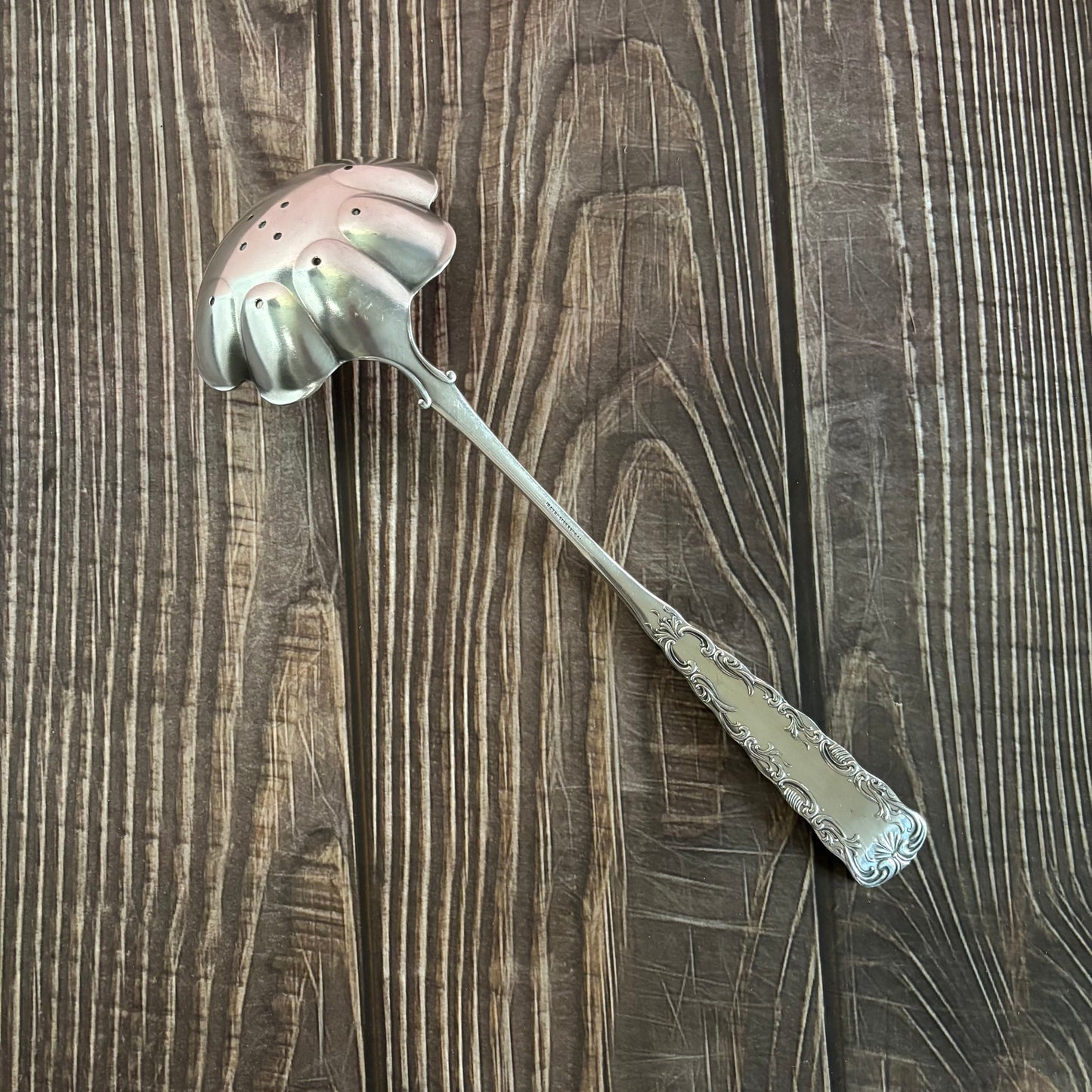 Decorative silver ladle on a wooden surface