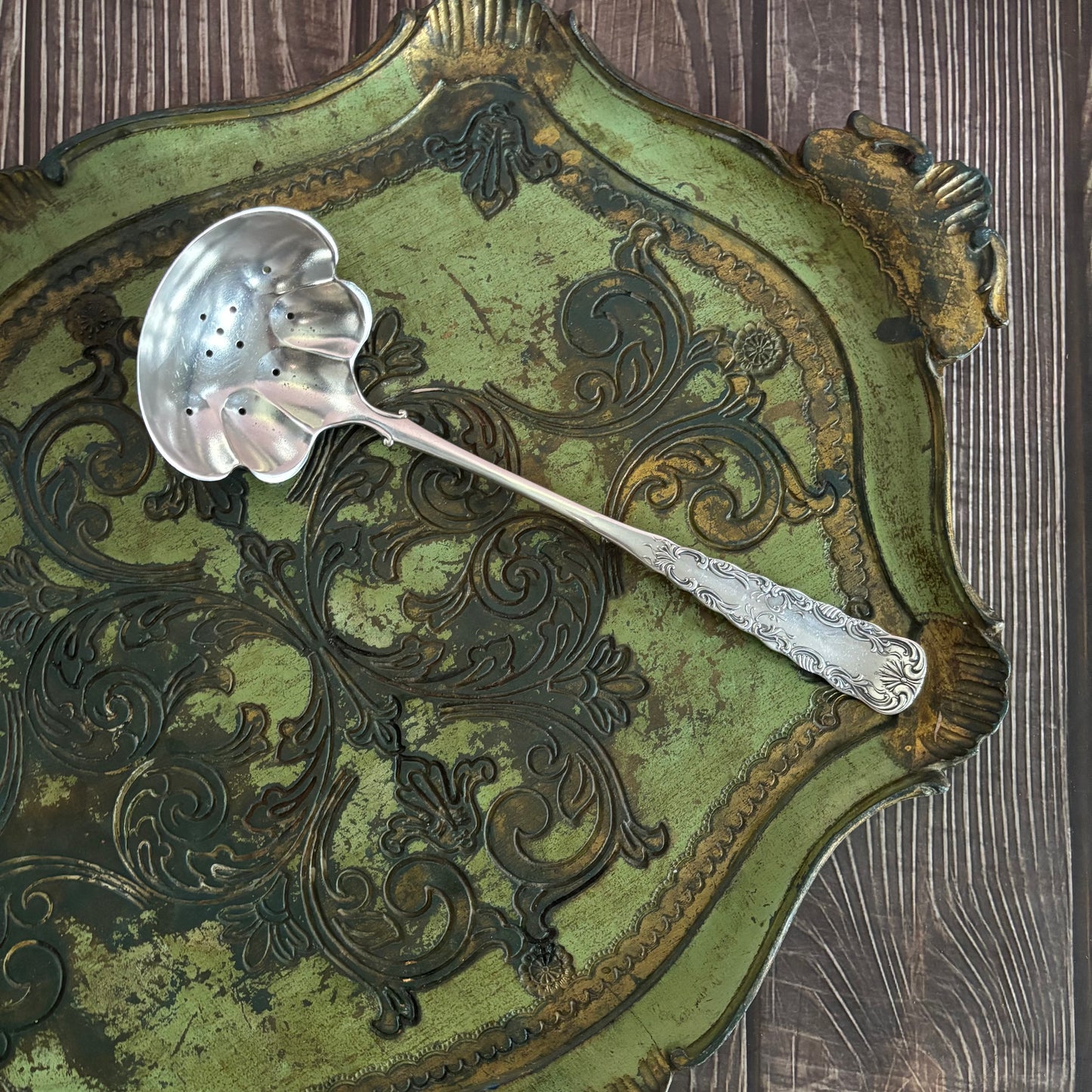 Decorative silver ladle on an ornate green and gold tray