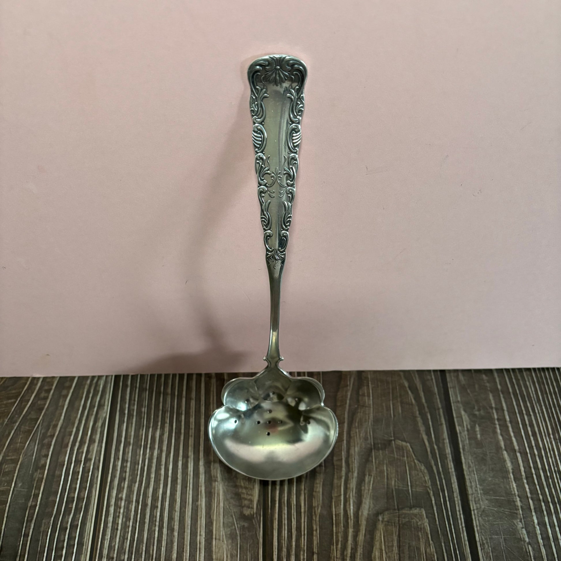 Decorative silver spoon on a wooden surface with a white background