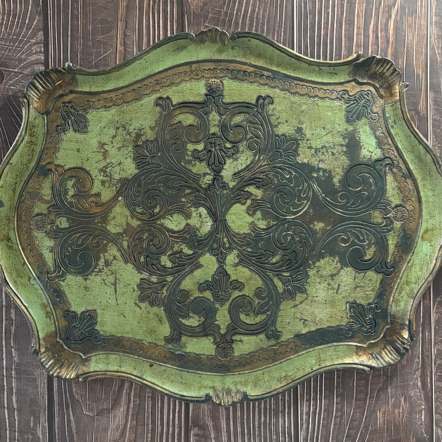 Decorative metal plaque with intricate designs on a wooden surface