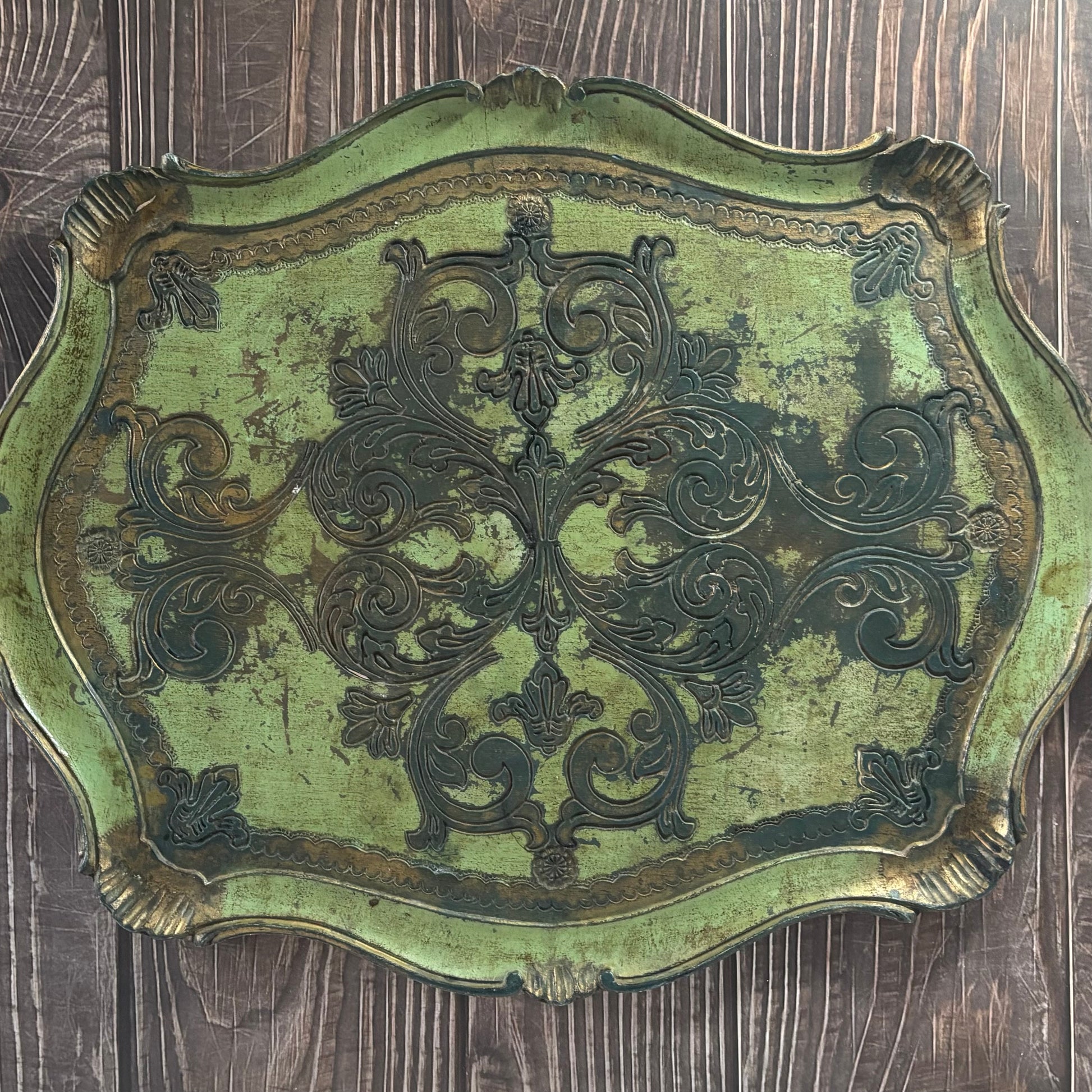Decorative metal plaque with intricate designs on a wooden surface