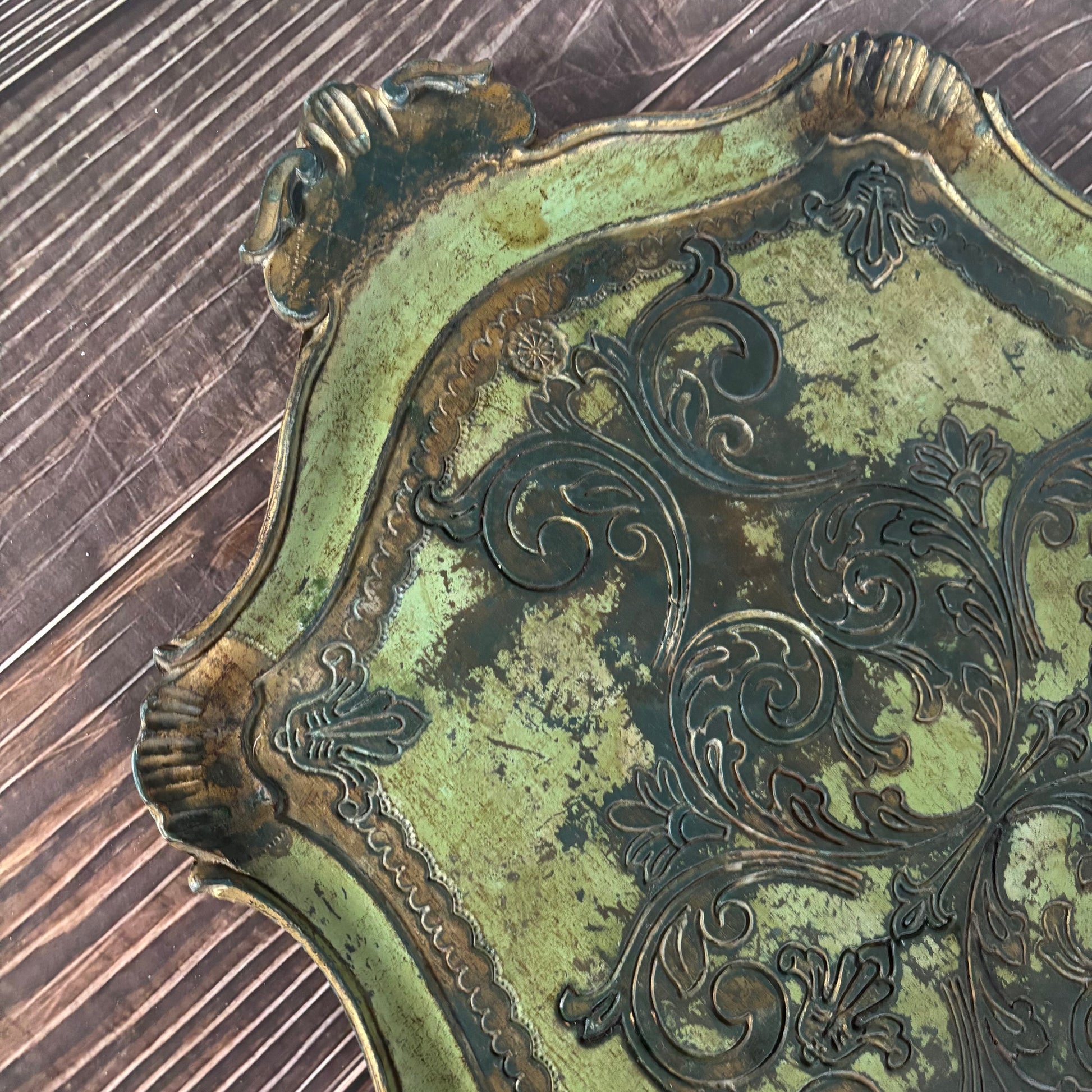 Close-up of an ornate metal object with intricate designs on a wooden surface.