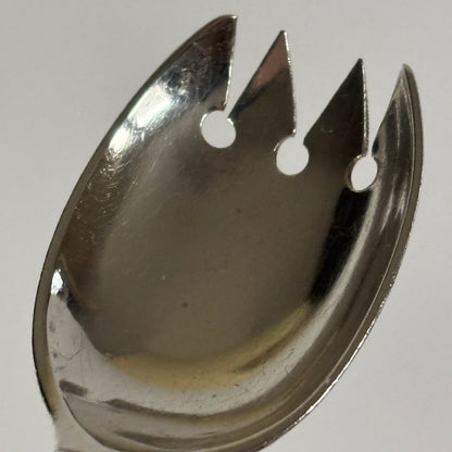 Metallic fish-shaped fork on a light gray background