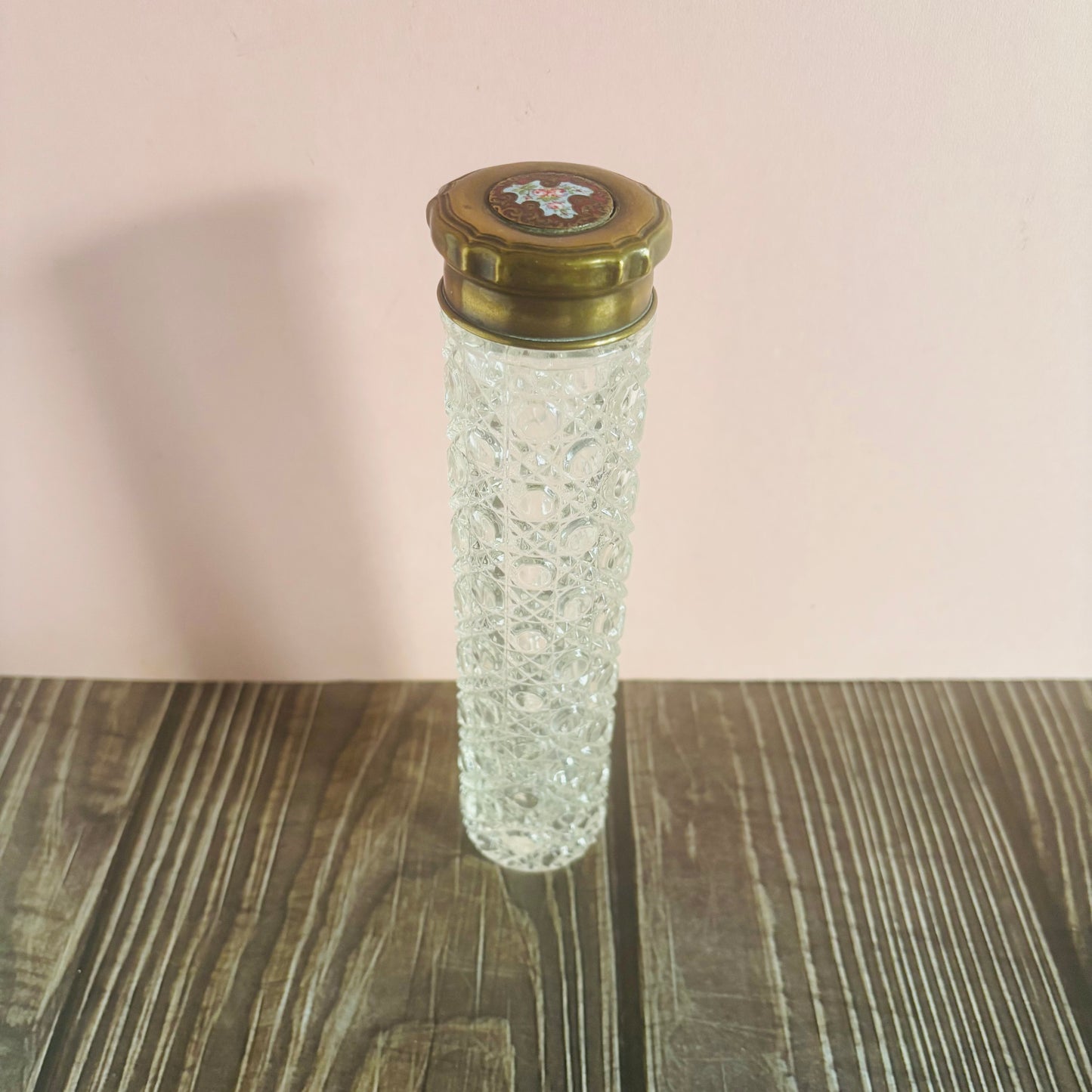Decorative glass bottle with a brass cap on a wooden surface
