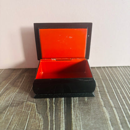Open red box with black interior on a striped surface