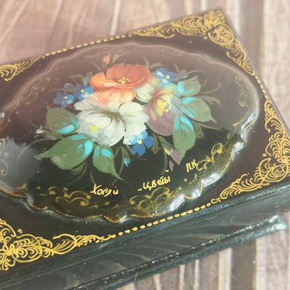 Decorative box with floral design and gold accents on a wooden surface