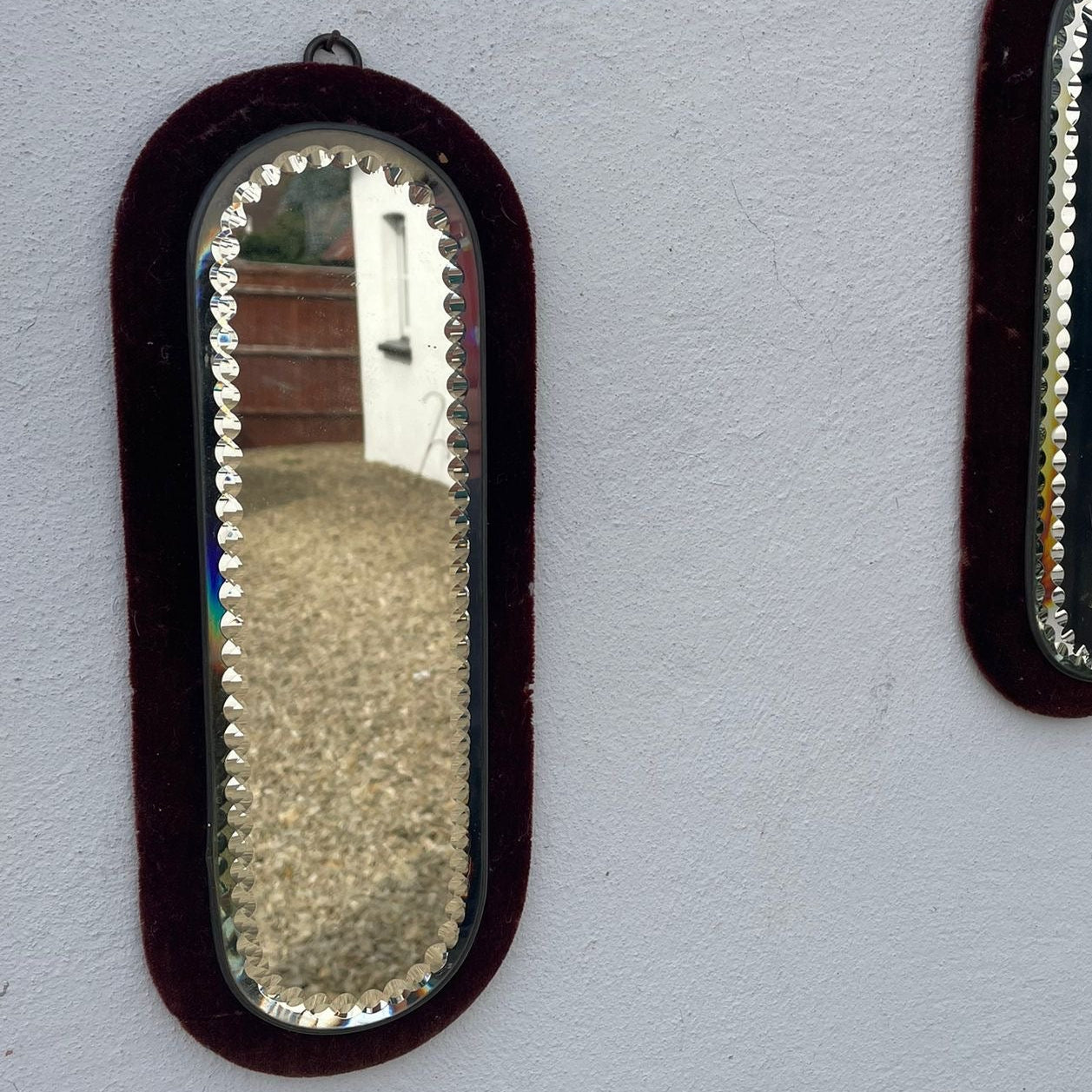Two oval mirrors with decorative frames on a light gray wall.