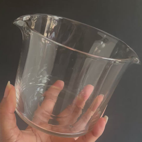Two clear glass antique cooling rinsers on a textured surface with a pink background
